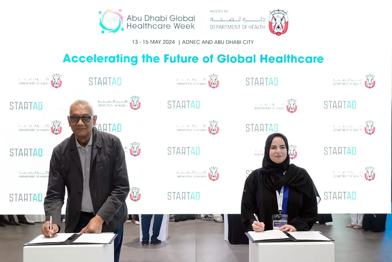Two representatives sign an agreement at the HealthX launch during Abu Dhabi Global Healthcare Week.